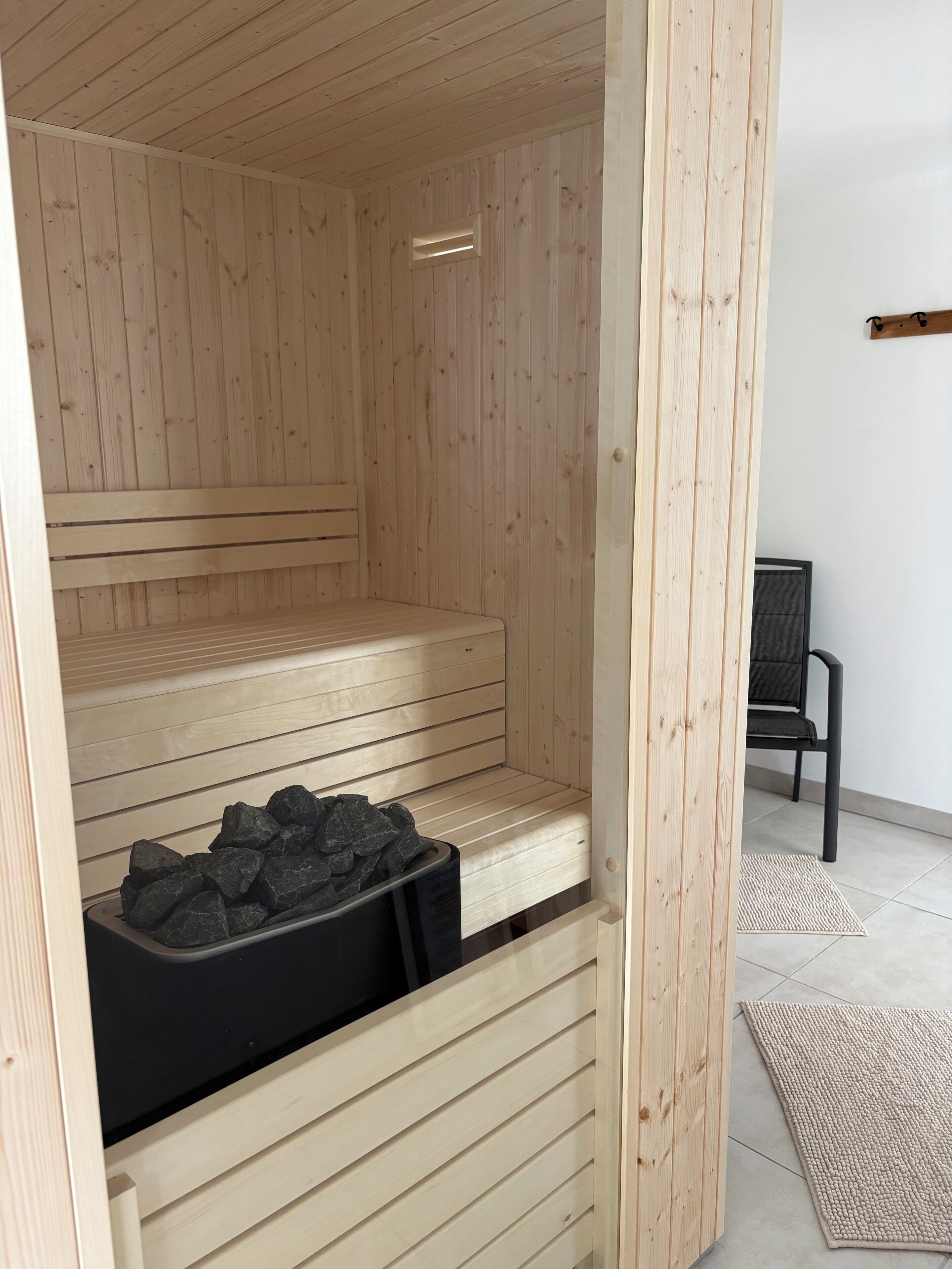 Een sauna met houten banken en een zwarte bak met stenen.