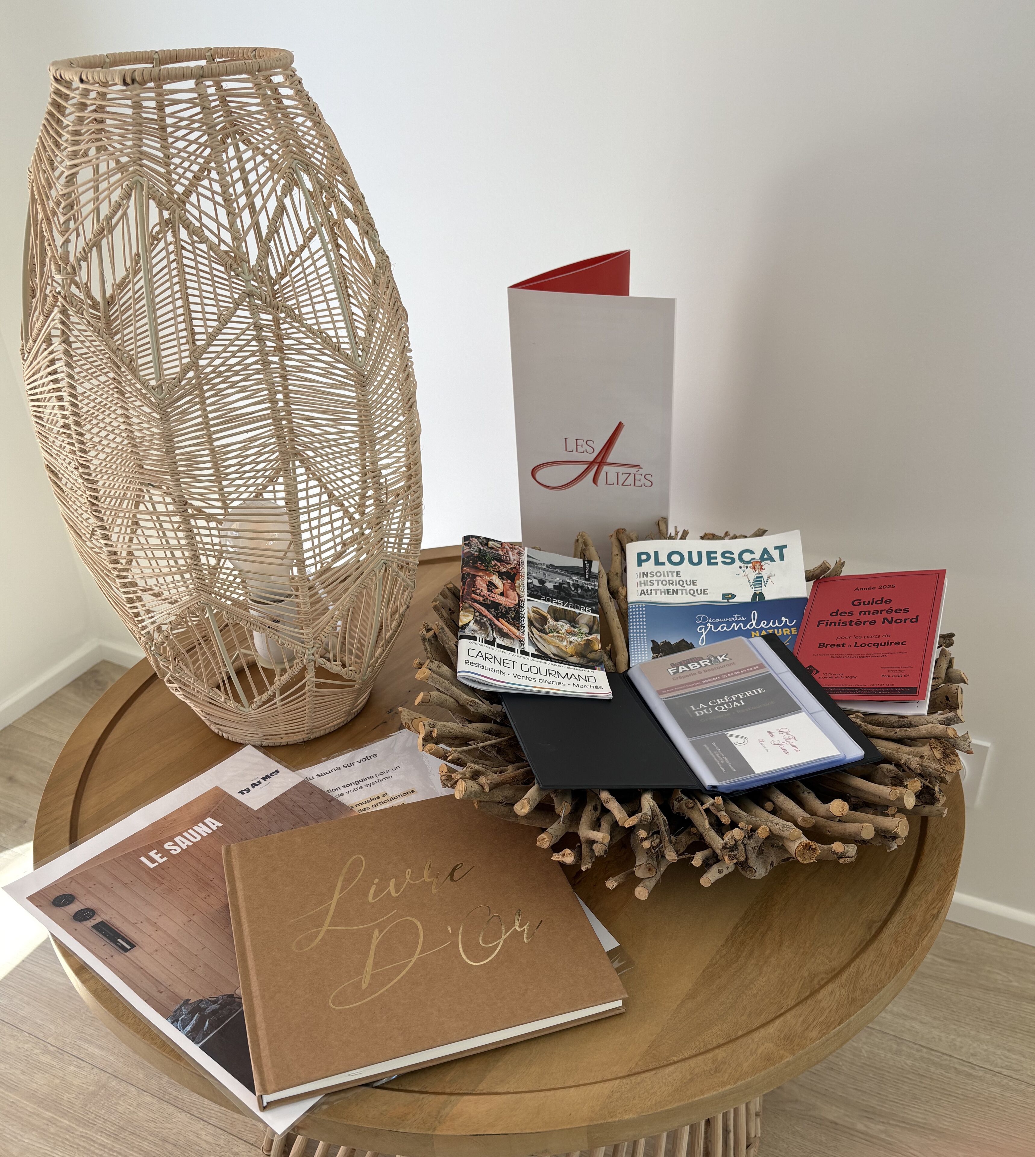 A wooden table with a woven basket, a book titled 'Le Sauna', and several brochures.