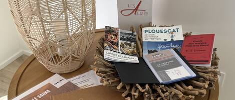 A wooden table with a woven basket, a book titled 'Le Sauna', and several brochures.