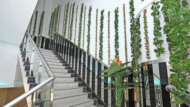 A staircase with a glass railing, surrounded by vertical greenery and potted plants. - Yijia Business Hotel (Shanghai)