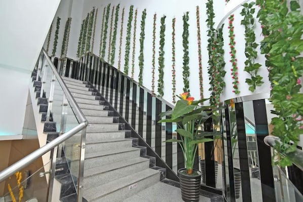 A staircase with a glass railing, surrounded by vertical greenery and a potted plant. - Yijia Business Hotel (Shanghai)