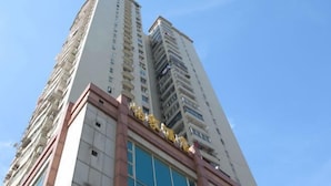 A tall hotel building with multiple floors and balconies. - Yijia Business Hotel (Shanghai)