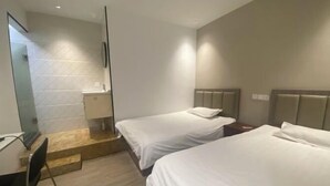 A hotel room with two single beds, a small desk, a chair, a mirror, and a shower area. - Yijia Business Hotel (Shanghai)