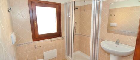 A bathroom with a toilet, a shower enclosure, and a sink.