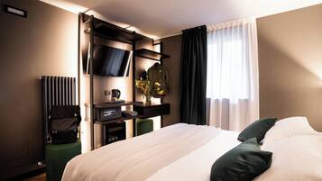 Habitación de hotel con una cama grande, un televisor de pantalla plana en la pared, un escritorio con una silla y un radiador.
