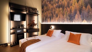 Une chambre d’hôtel avec un grand lit, un téléviseur à écran plat, une machine à café et une étagère fixée au mur.