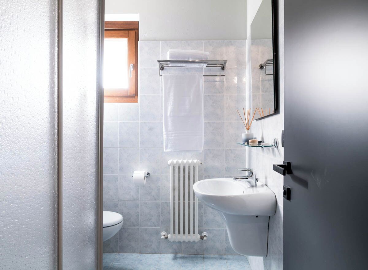 Une salle de bain équipée d’un WC, d’un lavabo, d’un miroir et d’un porte-serviettes.