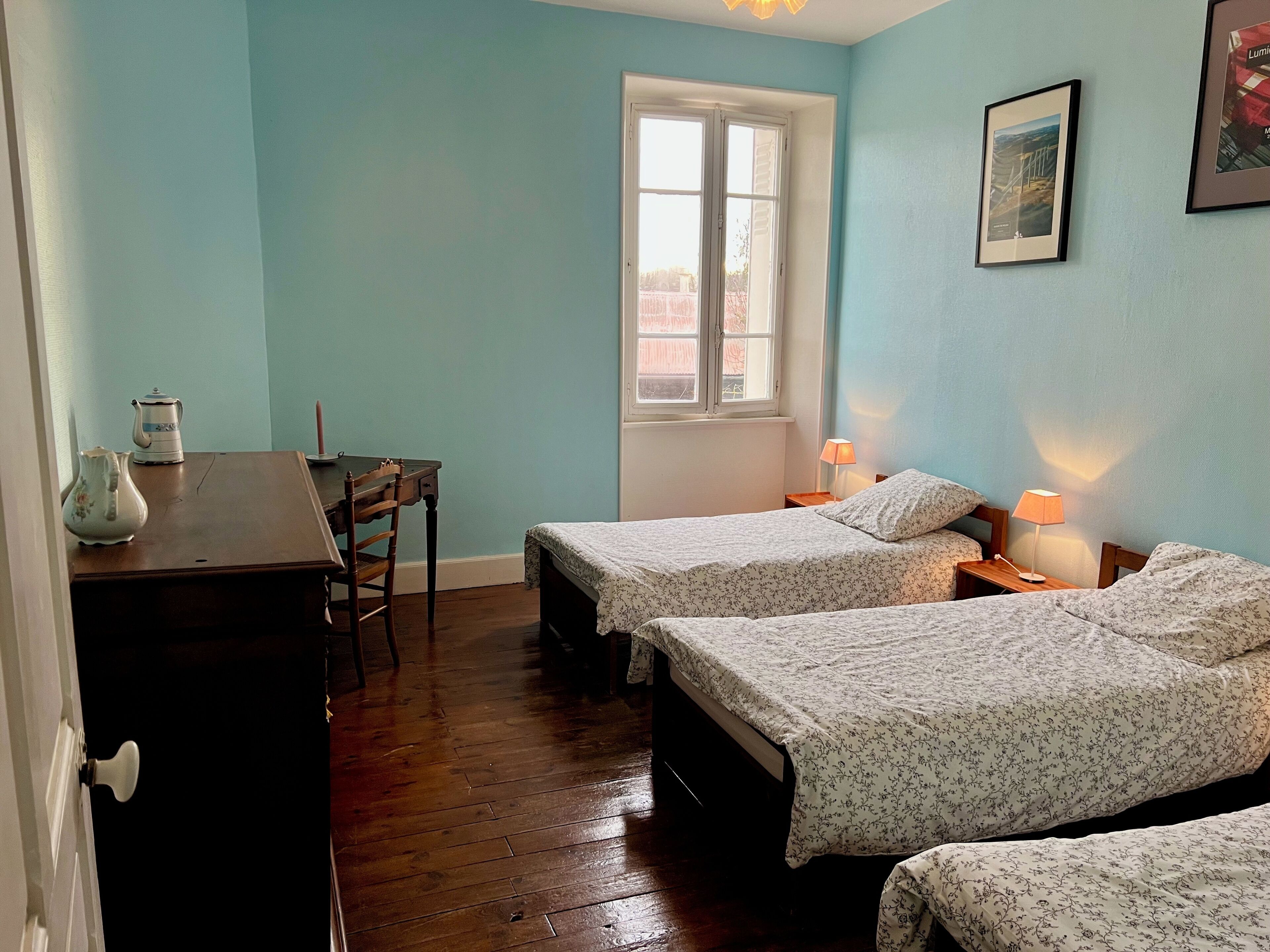 A room with two beds, a desk, a chair, and a window.