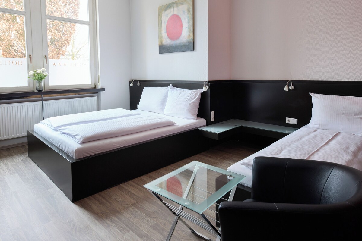 A modern hotel room with a large bed, a small table, and a chair.