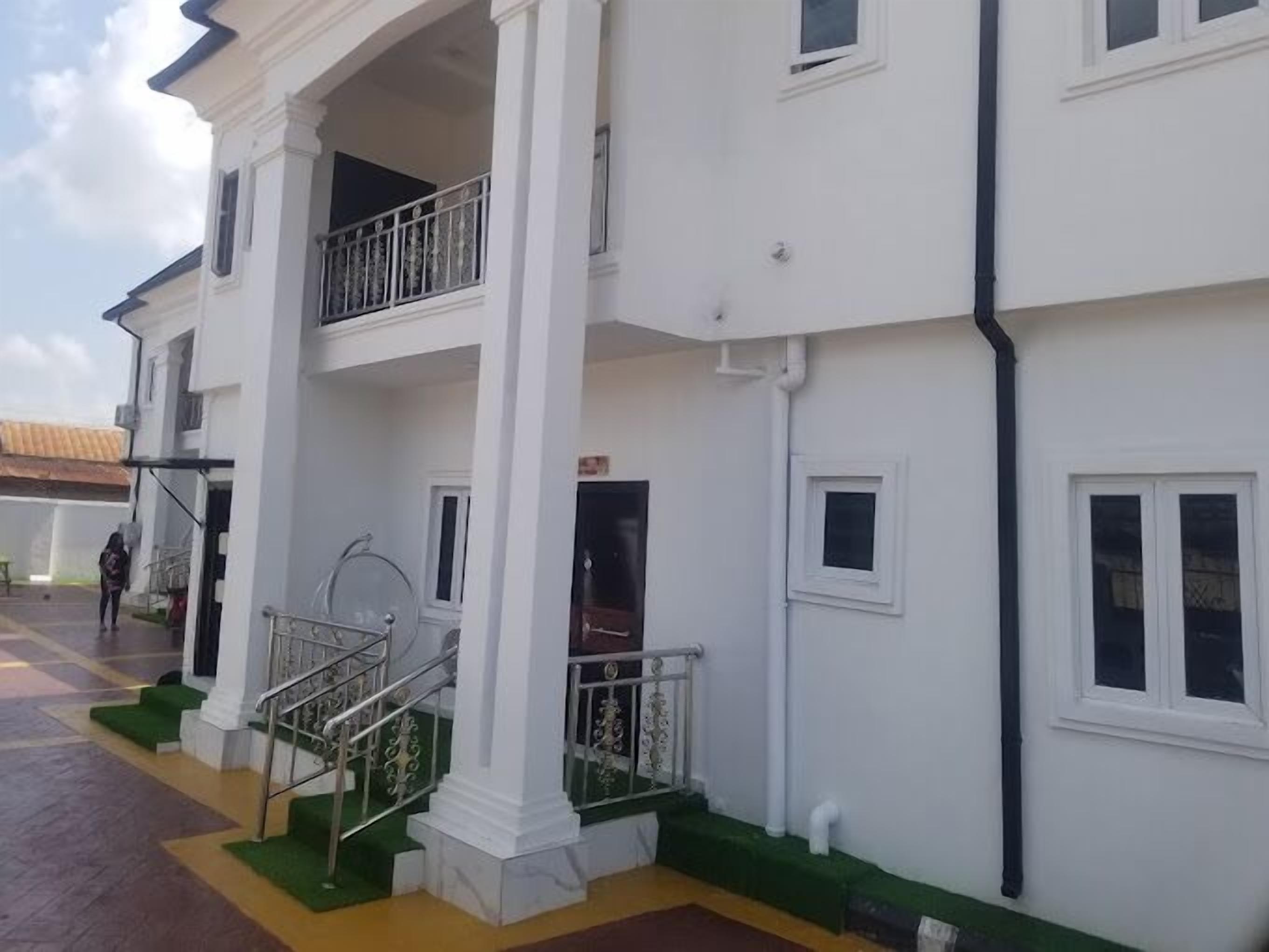 Un edificio de varios pisos con fachada blanca, un espacio al aire libre cubierto con escaleras y un balcón.