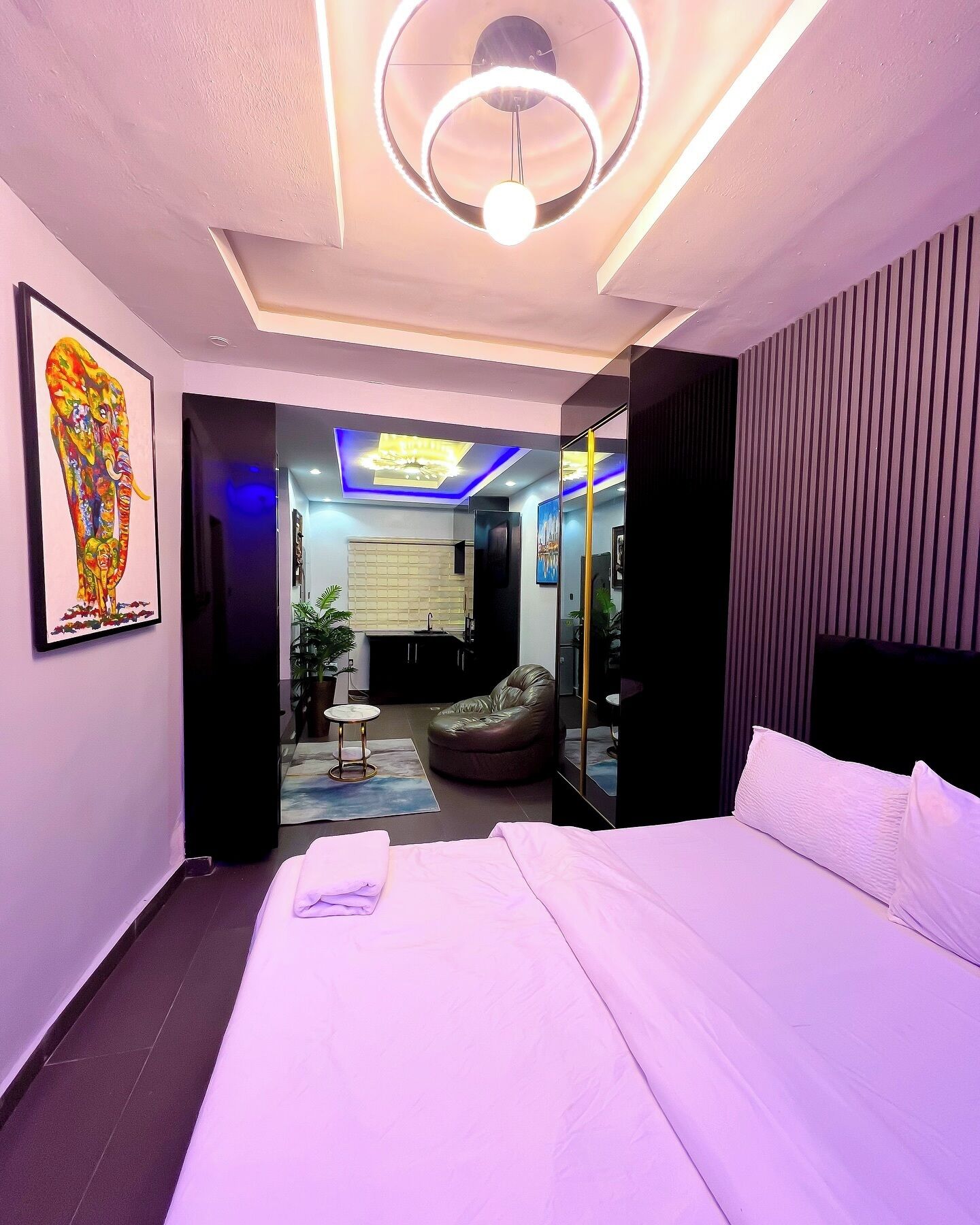 Een moderne hotelkamer met een groot bed, een zithoek en een plafondlamp.