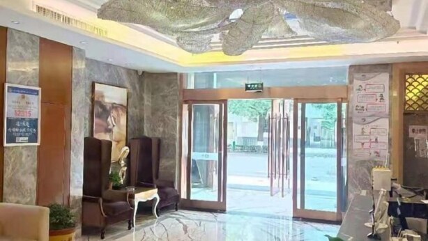 A hotel lobby with a marble floor, a reception desk, a seating area, and a glass door entrance. - Pingliang Rongting Hotel (Pingliang)