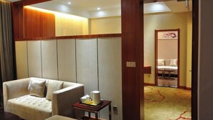 A hotel room with a sofa, a small table with a kettle, and a bed with a headboard. - Pingliang Rongting Hotel (Pingliang)