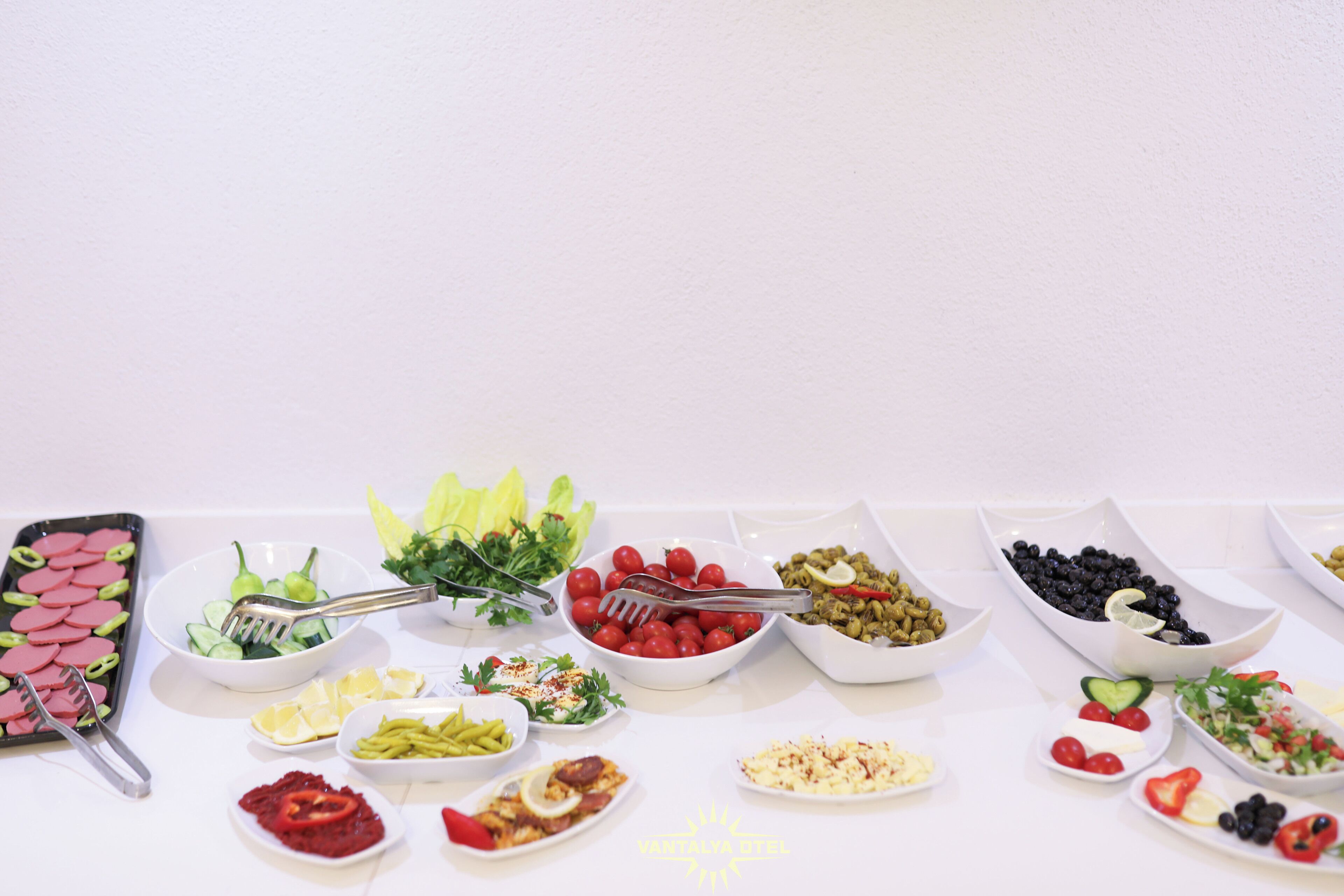 A variety of food items arranged on a table, including salads, fruits, and dips.