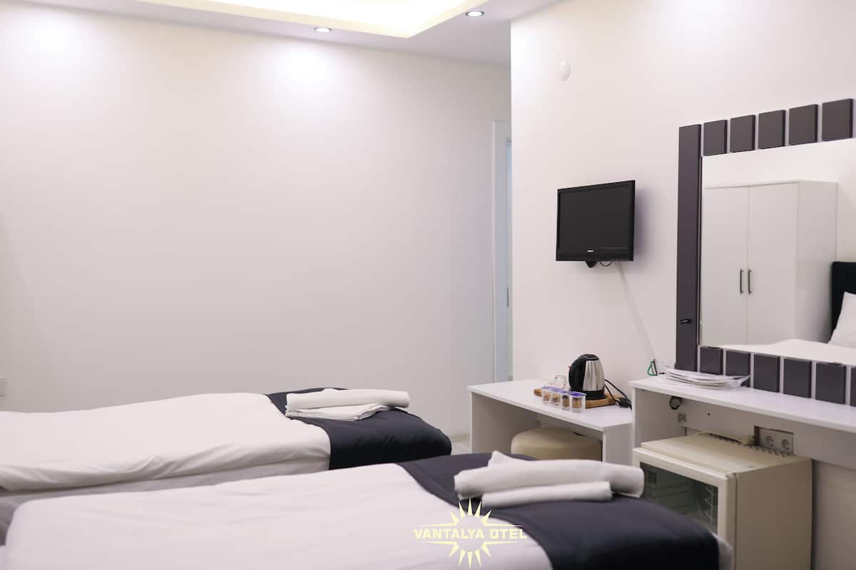 A hotel room with two beds, a desk, a TV, and a wardrobe.