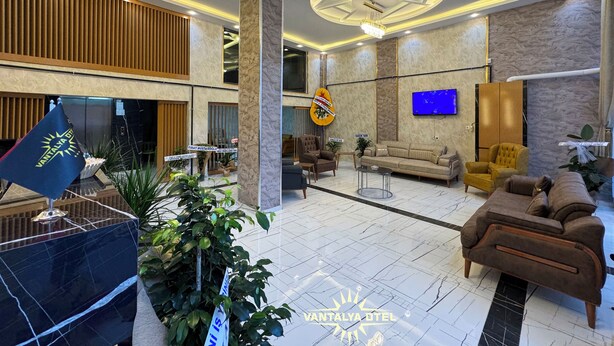 A hotel lobby with a reception desk, seating area, and a TV mounted on the wall. - Vantalya Otel (Van)