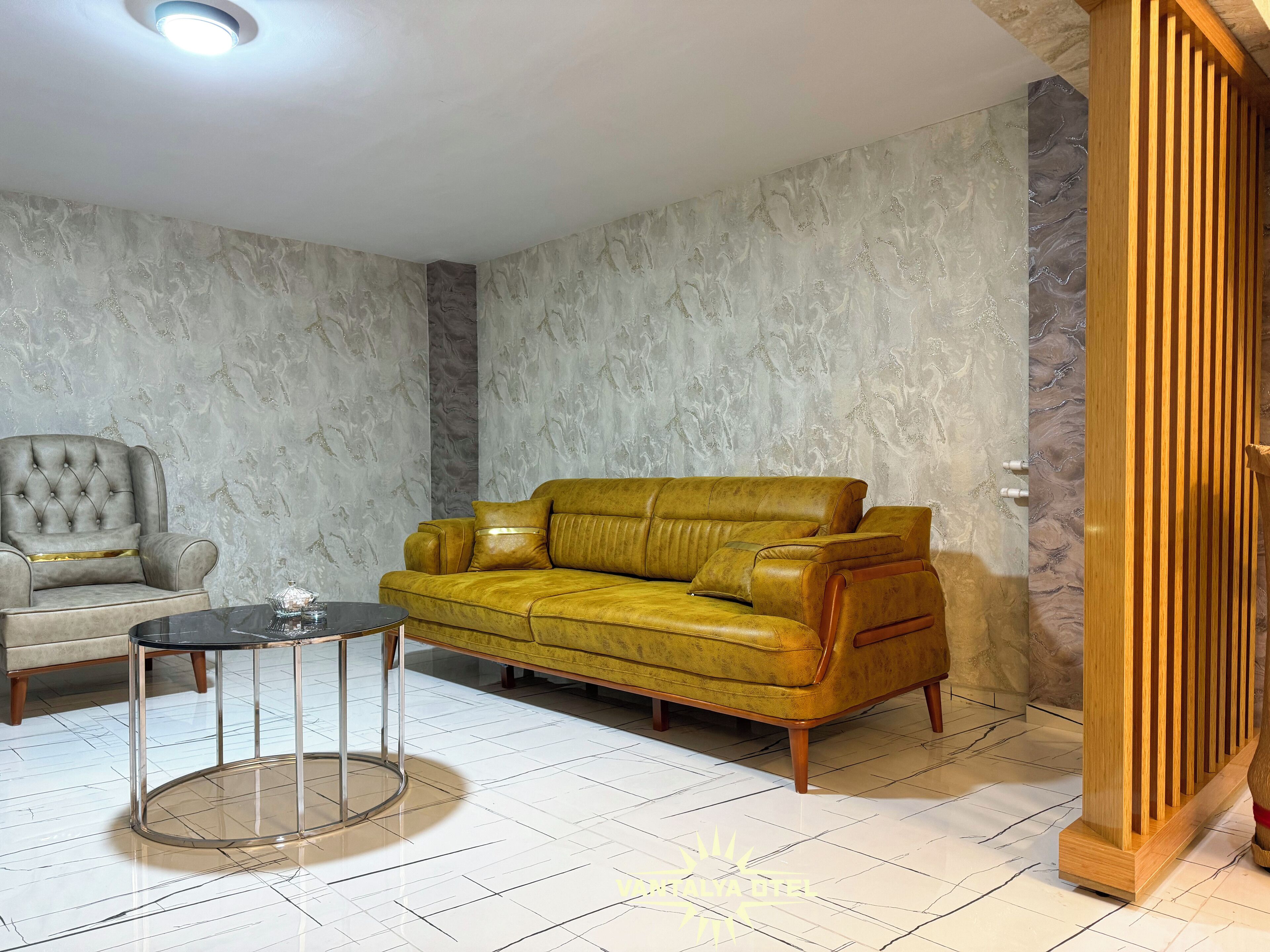 A living room with a yellow leather sofa, a grey armchair, and a glass-top coffee table.