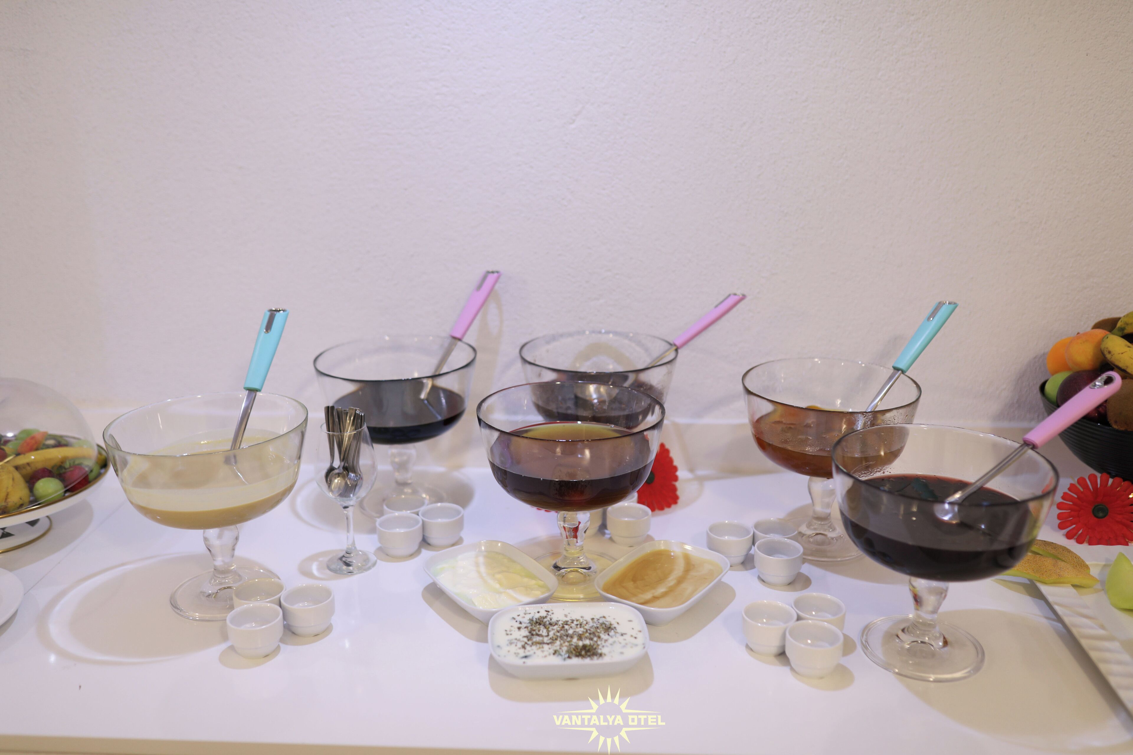 A table with various glasses of beverages and small dishes, likely for a tasting event.