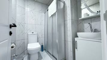 Un baño moderno con inodoro, ducha y lavamanos.