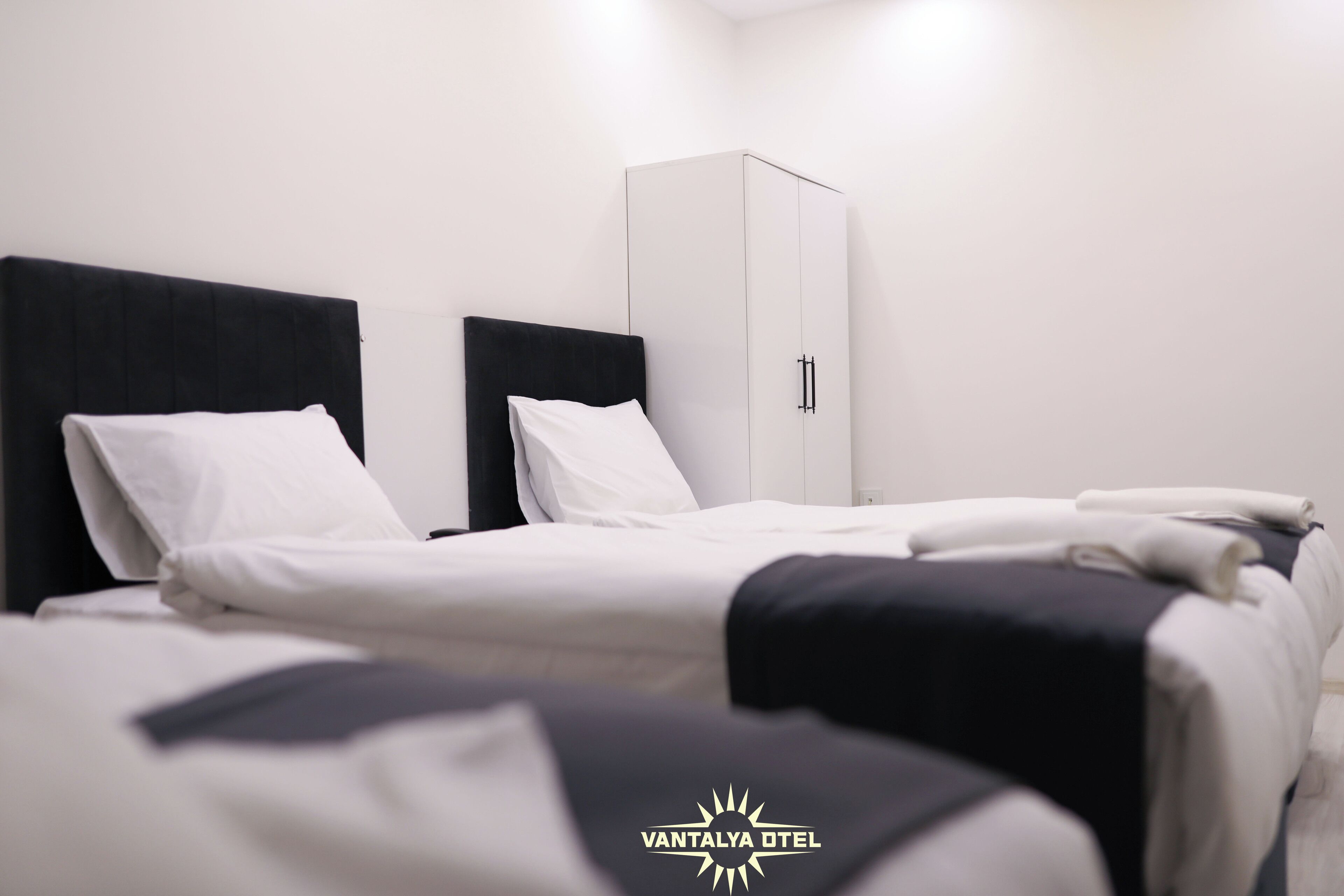 Una habitación de hotel con una cama, un armario y una pared blanca.