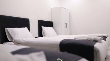 Una habitación de hotel con una cama, un armario y una pared blanca.