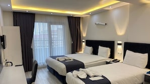 A hotel room with two beds, a desk, and a large window with curtains. - Vantalya Otel (Van)