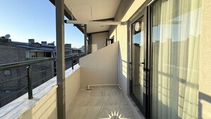 A balcony with a tiled floor, a glass door, and a metal railing. - Vantalya Otel (Van)