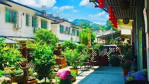 A narrow alley with potted plants and a wooden fence, leading to a building with a tiled roof. - Danxia Shanyang Yuancun Inn (core scenic spot) (Renhua)