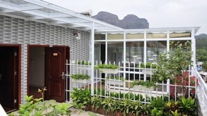 A modern building with a glass enclosure, a brick wall, and a white fence with plants. - Danxia Shanyang Yuancun Inn (core scenic spot) (Renhua)