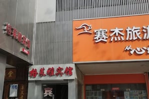 A hotel with signage in a foreign language, a visible entrance, and a large orange sign with white text. - Ge Lai Ya Hotel (Shanghai)