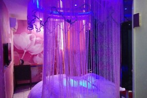 Ein Zimmer mit einem Himmelsbett, einem kleinen Tisch und einer Wand mit einem Ballonmuster.