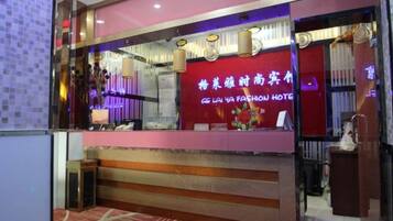 A hotel reception area with a red and purple color scheme, a reception desk, and a sign in a foreign language.