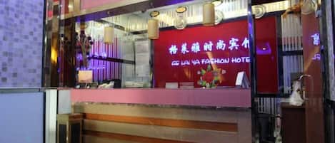 A hotel reception area with a red and purple color scheme, a reception desk, and a sign in a foreign language.
