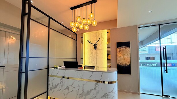 A reception desk with a marble finish, a mounted deer head, and a chandelier with multiple bulbs. - Hotel Fun Regency (Ahmedabad)
