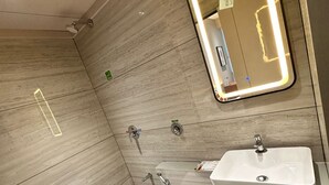 A modern bathroom with a large mirror, a sink, a bidet, and a toilet. - Hotel Fun Regency (Ahmedabad)