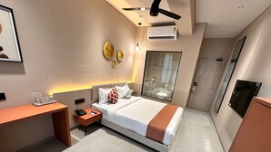 A modern hotel room with a bed, bedside table, and a desk. - Hotel Fun Regency (Ahmedabad)