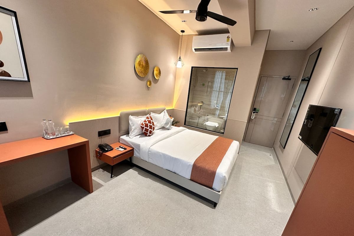 A modern hotel room with a bed, bedside table, and a desk.