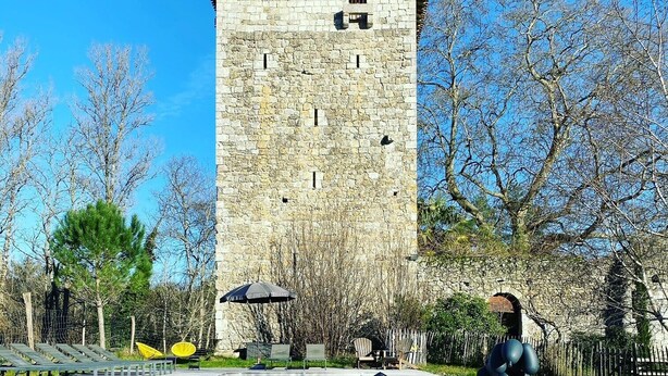 A stone tower with a swimming pool in front.