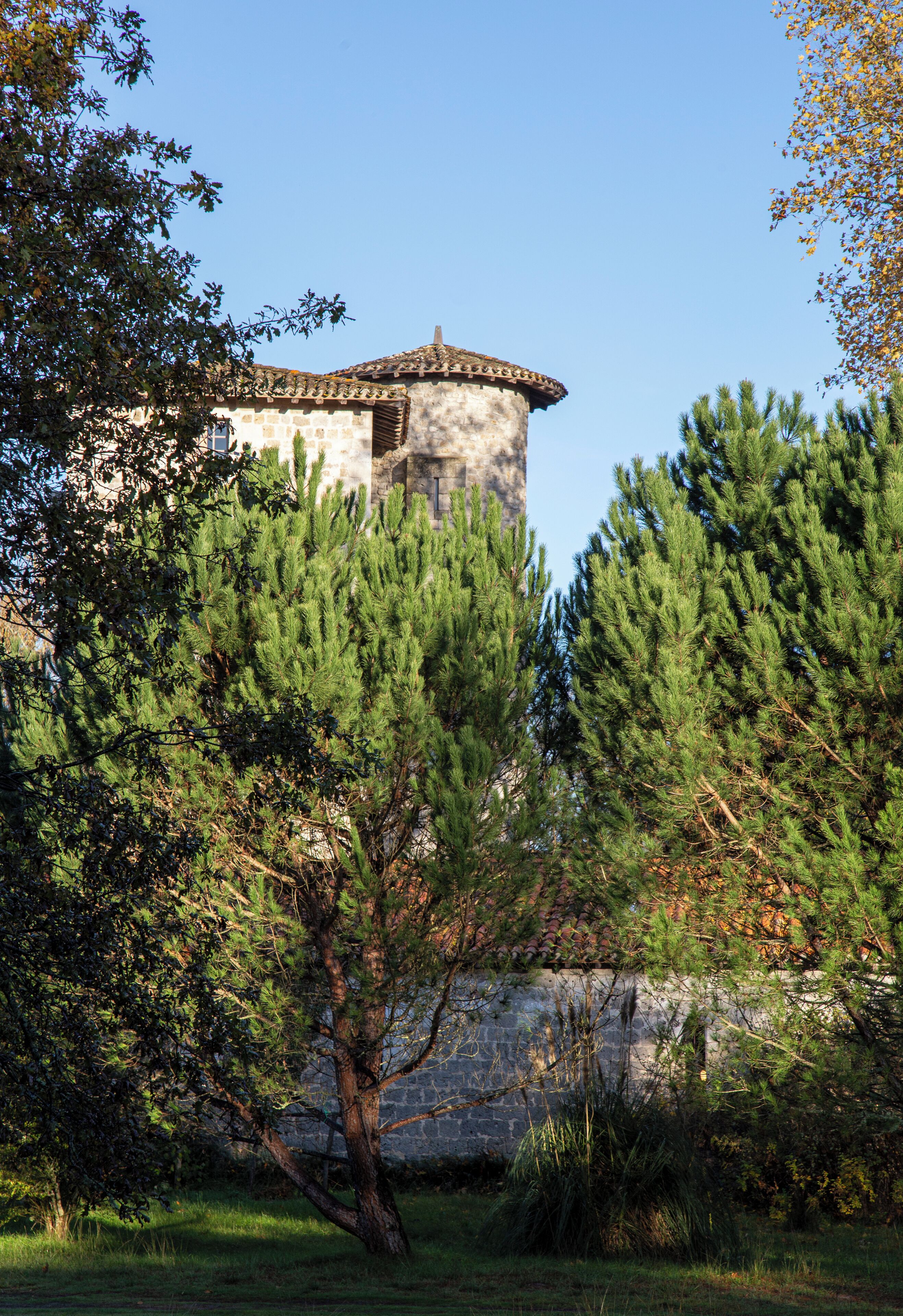 Ein Gebäude aus Stein mit Ziegeldach, umgeben von Bäumen und Gras.
