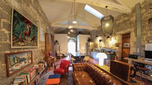 A rustic interior with a leather sofa, bookshelves, and a dining area.