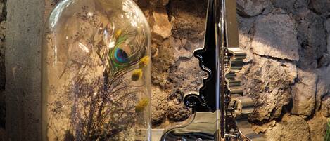 A lamp with a reflective surface and a glass enclosure containing a plant and a peacock feather.