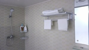 A bathroom with a shower, a towel rack, and a glass shelf with toiletries. - Huike Hostel (Shanghai)