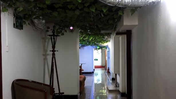 A hallway with a tripod, a chair, and a bench. - Huike Hostel (Shanghai)