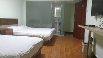 Habitación de hotel con dos camas, piso de madera, televisor, lavamanos y espejo.