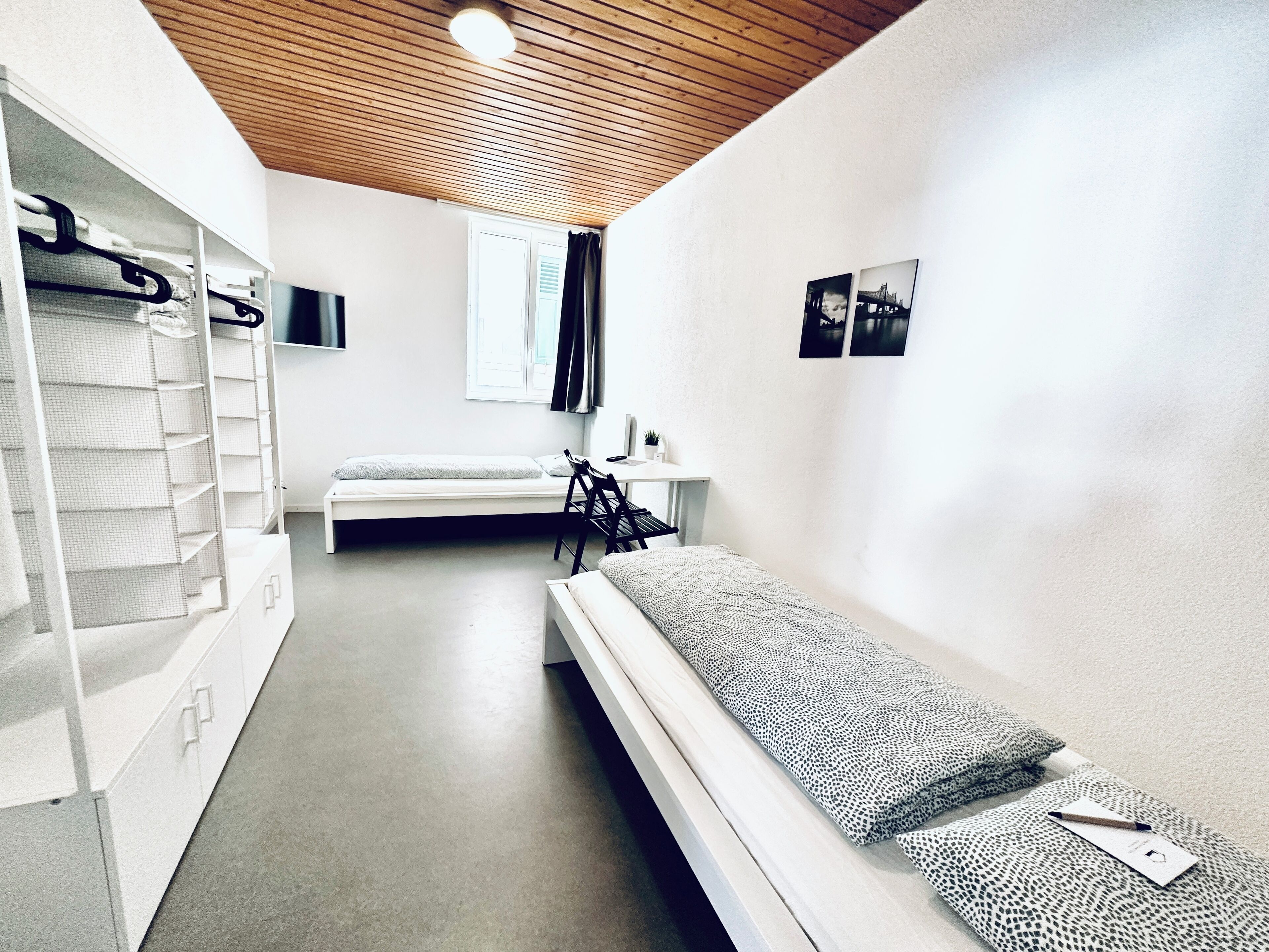 A minimalist room with a bunk bed, a desk, and a shelving unit.