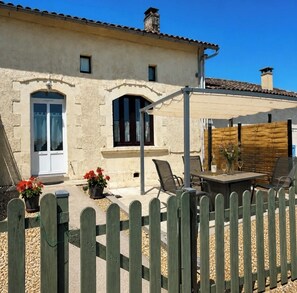 A rustic building with a patio, outdoor seating, and a wooden fence.