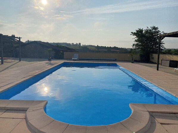 A rectangular swimming pool with a curved edge, surrounded by a tiled deck.
