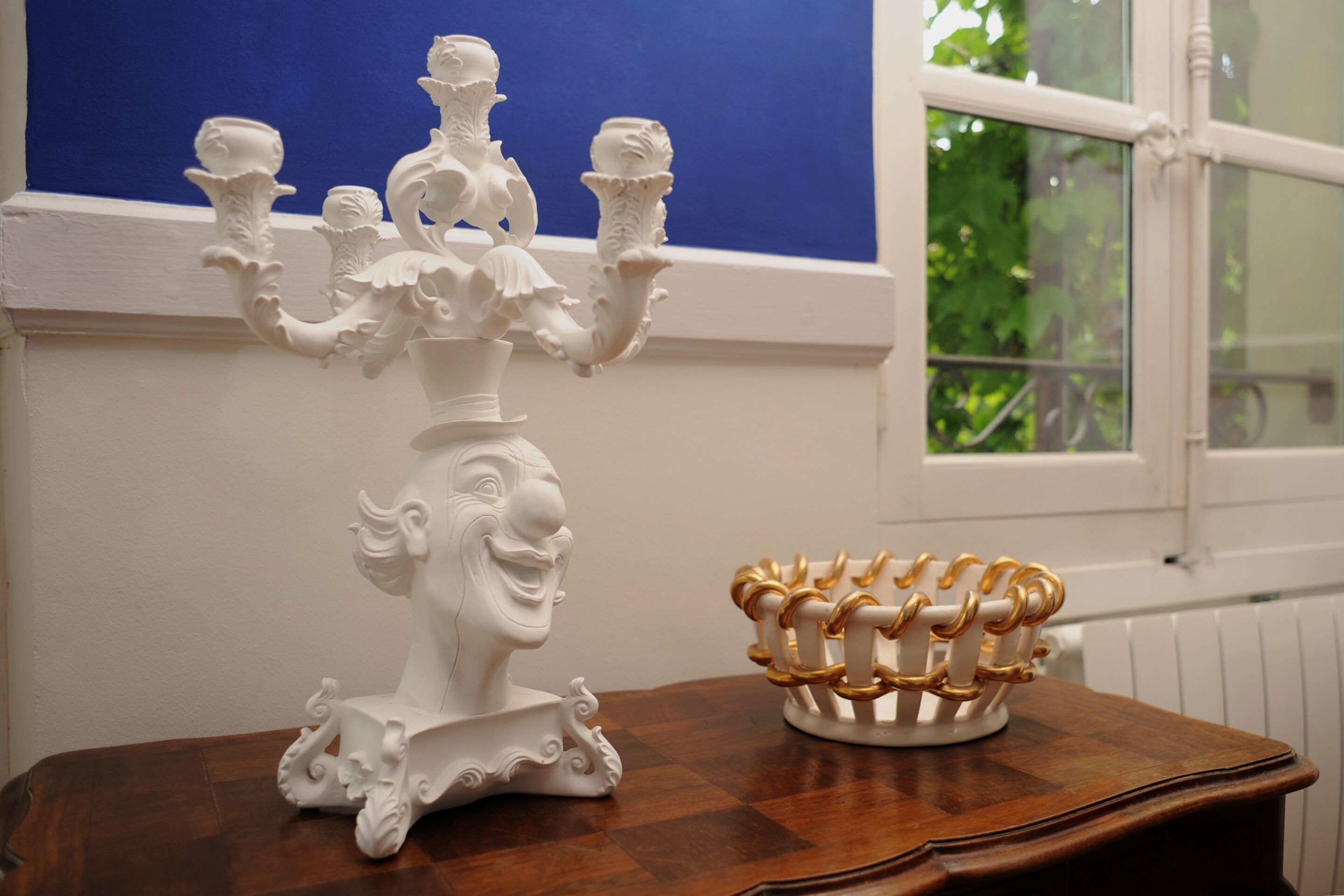 Un chandelier blanc aux motifs complexes, posé sur une table en bois.