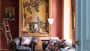 Una habitación con dos sillones de cuero, una escalera de madera, un espejo y un cuadro decorativo grande.