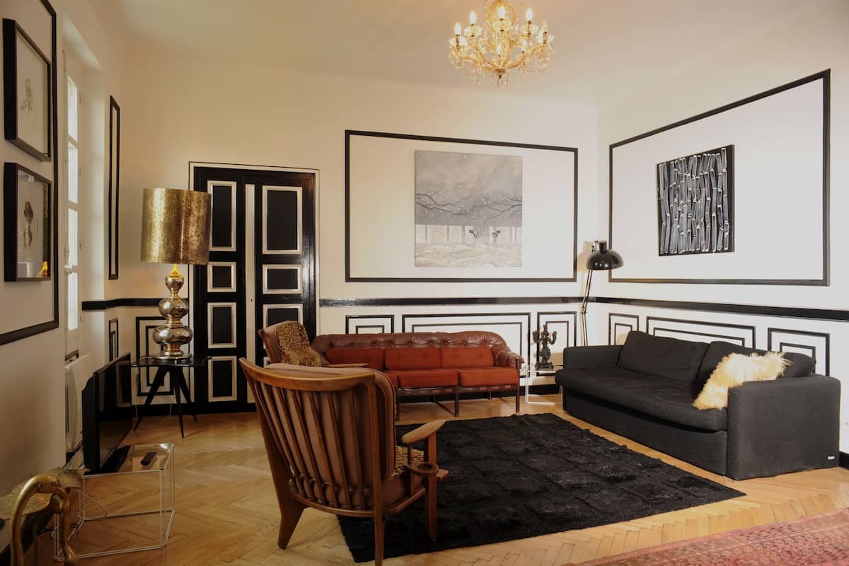 A living room with a black and white decor, a red sofa, a wooden chair, and a black rug.